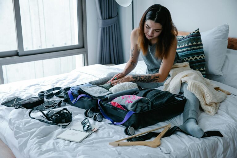 Woman Sitting on Bed at Home Packing Suitcase